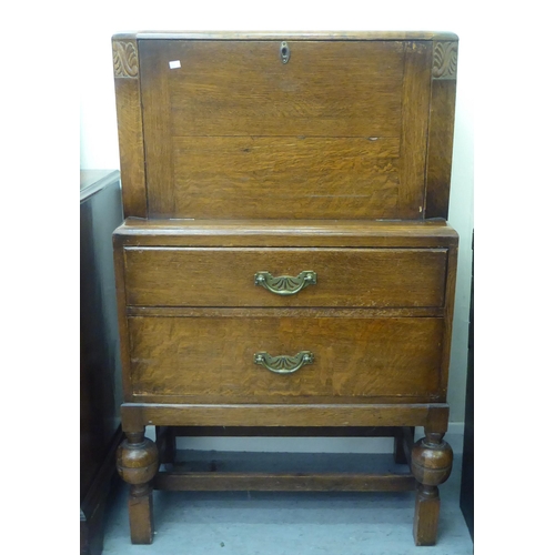 213 - A 1930s oak bureau with a fall front and two drawers, raised on bulbous, turned legs  43