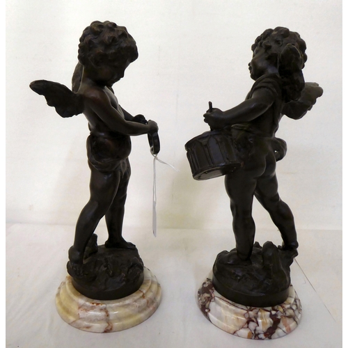 223 - A pair of bronze cherubic figures, posing with instruments, each raised on a marble plinth  bears in... 