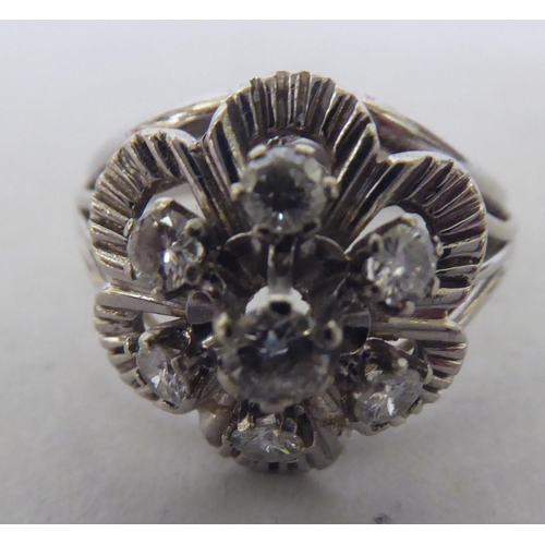 240 - A white metal (probably 18ct) floral design ring, set with seven diamonds