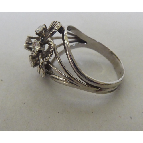 240 - A white metal (probably 18ct) floral design ring, set with seven diamonds