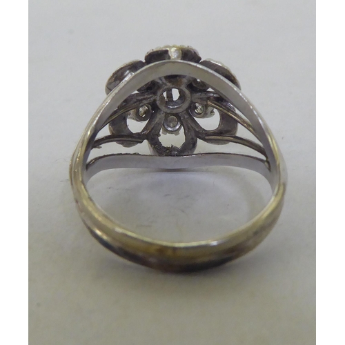 240 - A white metal (probably 18ct) floral design ring, set with seven diamonds