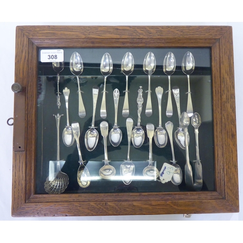 308 - A presentation case with a deep set, glazed oak door, containing silver teaspoons