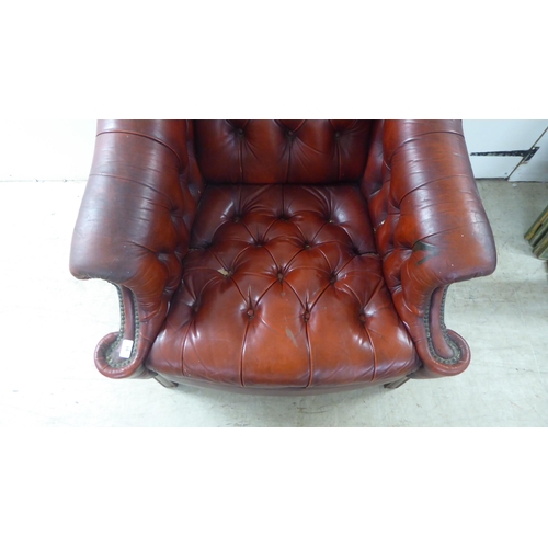 91 - A 20thC buttoned red fabric upholstered enclosed armchair, raised on square forelegs