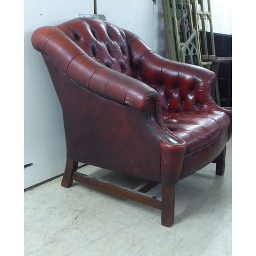 91 - A 20thC buttoned red fabric upholstered enclosed armchair, raised on square forelegs