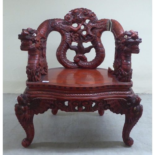 96 - A 20thC Sino-European red stained and profusely carved round back chair, featuring entwined dragons,... 