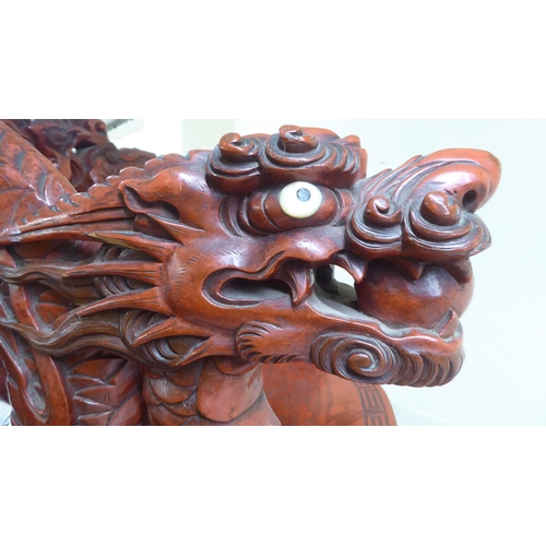 96 - A 20thC Sino-European red stained and profusely carved round back chair, featuring entwined dragons,... 