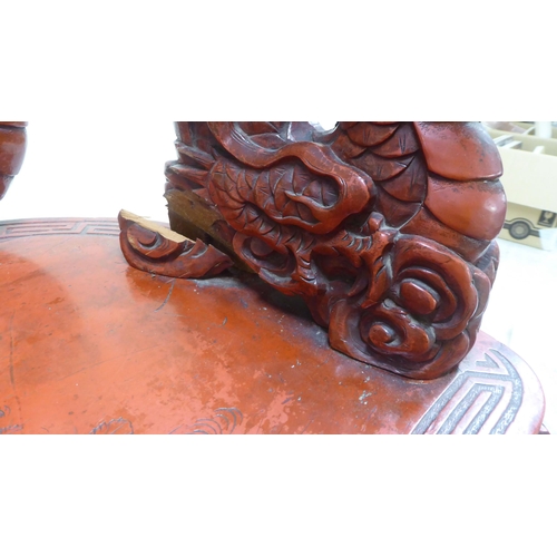 96 - A 20thC Sino-European red stained and profusely carved round back chair, featuring entwined dragons,... 