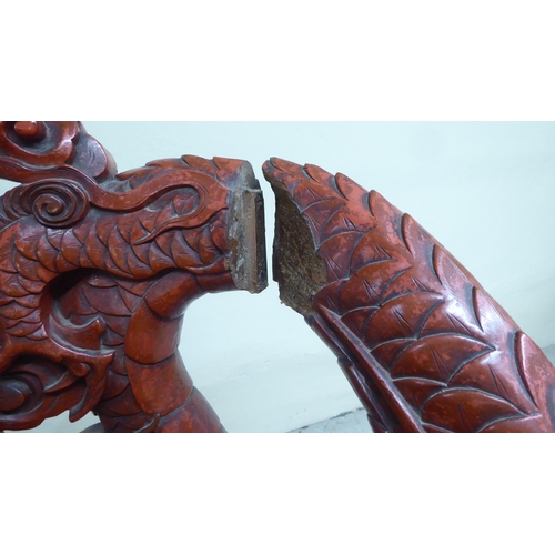 96 - A 20thC Sino-European red stained and profusely carved round back chair, featuring entwined dragons,... 