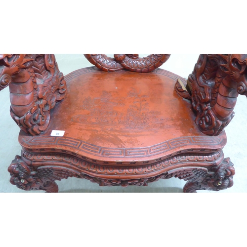 96 - A 20thC Sino-European red stained and profusely carved round back chair, featuring entwined dragons,... 