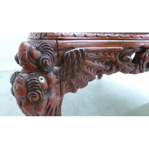 96 - A 20thC Sino-European red stained and profusely carved round back chair, featuring entwined dragons,... 