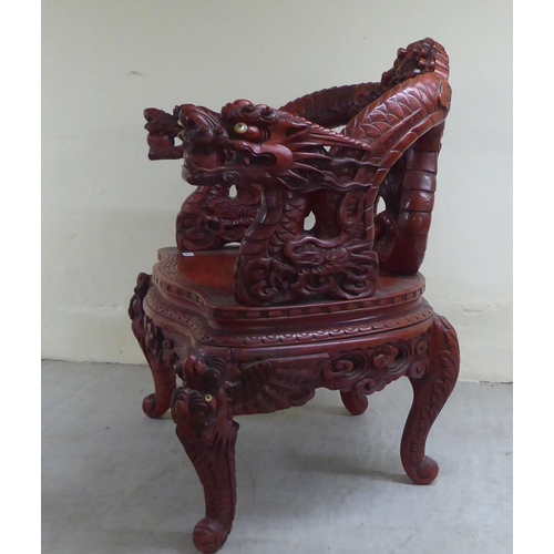 96 - A 20thC Sino-European red stained and profusely carved round back chair, featuring entwined dragons,... 