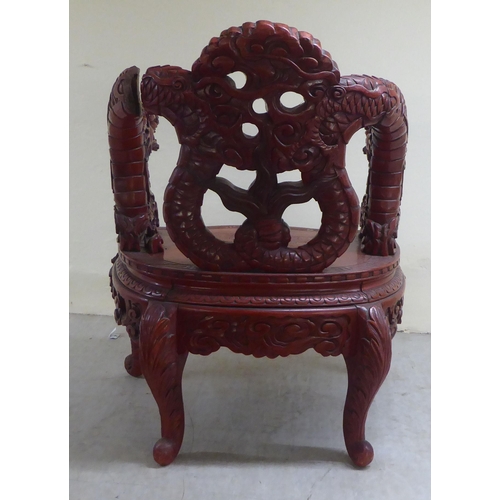 96 - A 20thC Sino-European red stained and profusely carved round back chair, featuring entwined dragons,... 