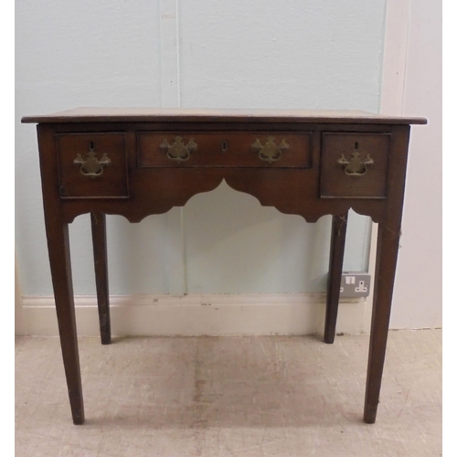 137 - A 19thC country made carved oak lowboy with a planked top, over one central and two flank box drawer... 