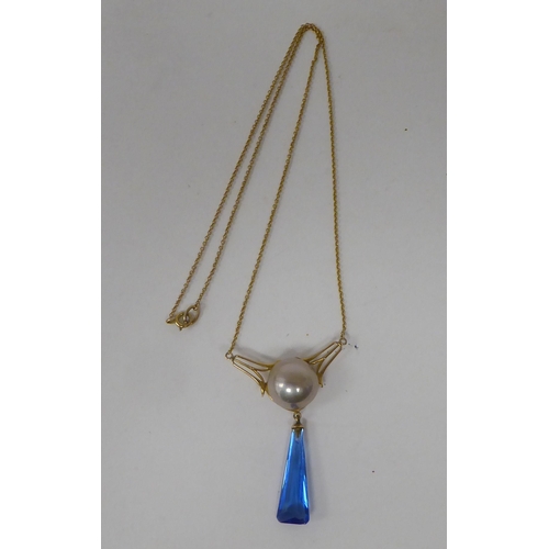 143 - An Art Deco design gold coloured metal necklace, set with a cabochon pearl and blue stone pendant, o... 