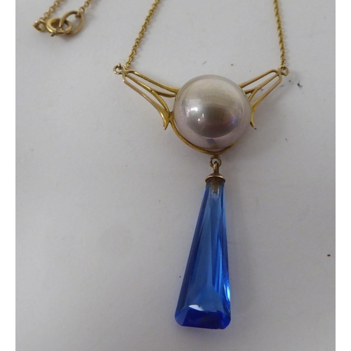 143 - An Art Deco design gold coloured metal necklace, set with a cabochon pearl and blue stone pendant, o... 