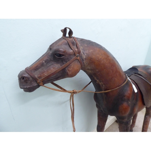 147 - A burnished and moulded hide standing, saddled and bridled model horse  approx. 37