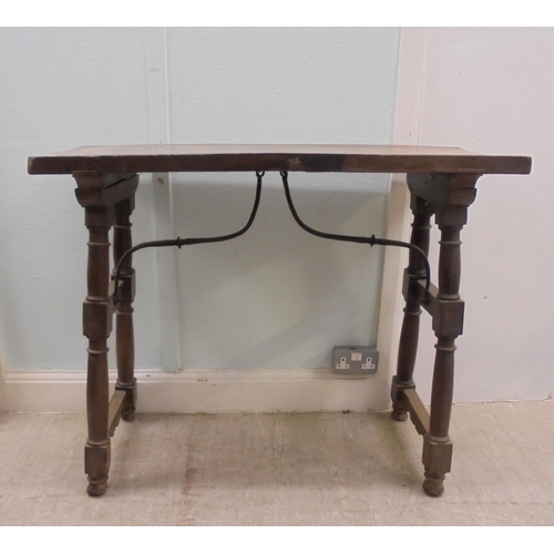 166 - A 19thC Spanish rustically constructed walnut serving table, the planked top raised on splayed, ring... 