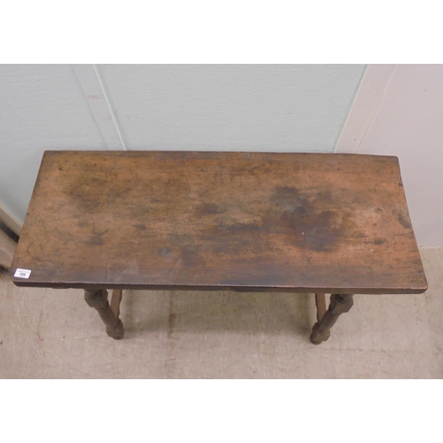 166 - A 19thC Spanish rustically constructed walnut serving table, the planked top raised on splayed, ring... 