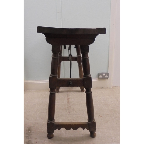 166 - A 19thC Spanish rustically constructed walnut serving table, the planked top raised on splayed, ring... 