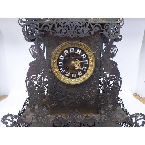 175 - A Continental fretworked brass cased mantel clock, featuring nude term figures, heraldic lions, flor... 