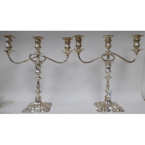 183 - A pair of Georgian style, two-part silver candelabra, each comprising a central socket and two scrol... 