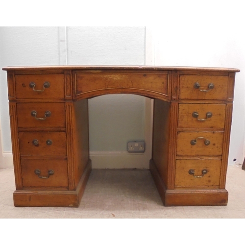 185 - An early 20thC satin mahogany nine drawer, twin pedestal desk with a green hide scriber and brass ba... 