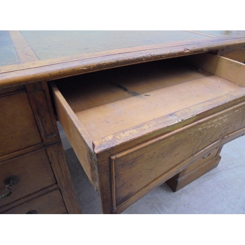 185 - An early 20thC satin mahogany nine drawer, twin pedestal desk with a green hide scriber and brass ba... 