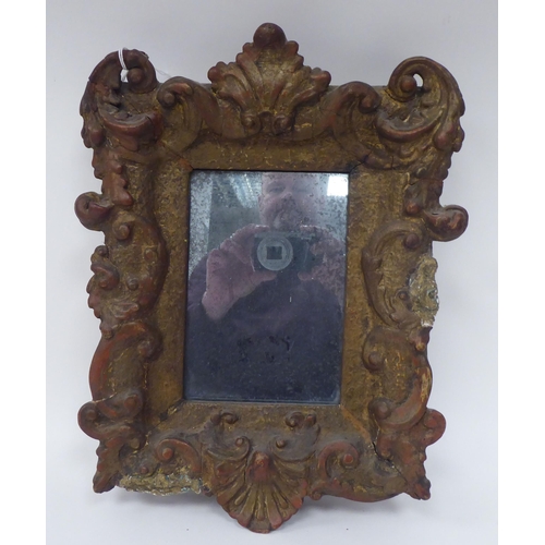 186 - A 19thC mirror, the plate set in a wide, gilt gesso frame, decorated with shell and scrolled ornamen... 