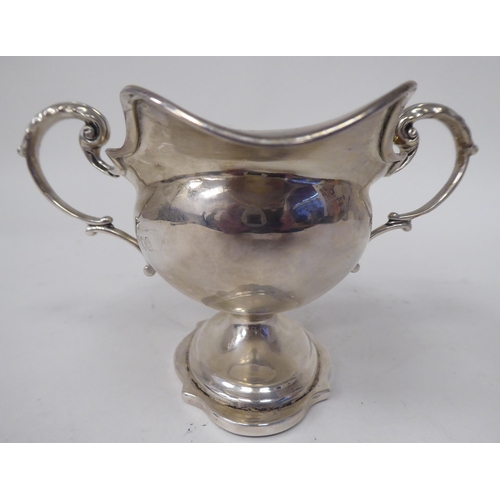 20 - An Edwardian silver sauce boat of oval pedestal form with opposing loop handles and pouring lips&nbs... 