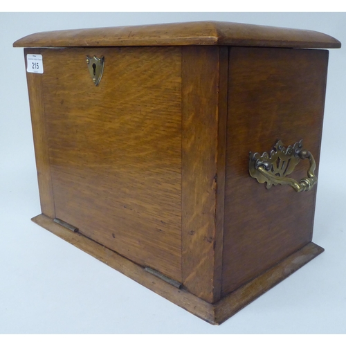 215 - A 1920s honey coloured oak cased desktop stationary box with opposing cast brass bail handles, a ris... 