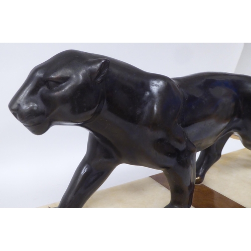 228 - After Rochard - an Art Deco patinated spelter model, a prowling panther, on a multi-coloured alabast... 