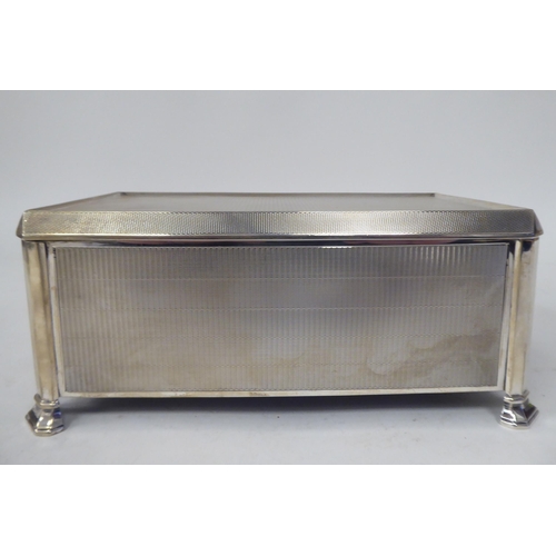 246 - A silver engine turned cigarette box with chamfered corners, straight sides and a hinged lid, enclos... 