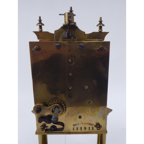 272 - A German made, lacquered brass cased torsion timepiece, the exposed movement on twin pillars, faced ... 