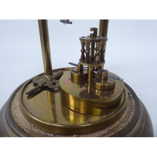 272 - A German made, lacquered brass cased torsion timepiece, the exposed movement on twin pillars, faced ... 