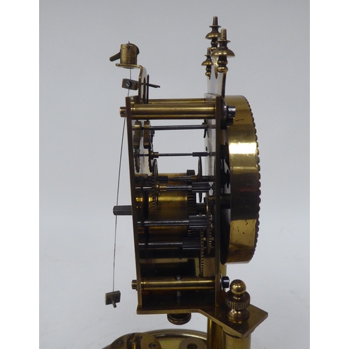 272 - A German made, lacquered brass cased torsion timepiece, the exposed movement on twin pillars, faced ... 