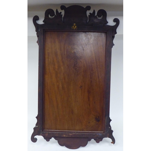 275 - An early 20thC Chippendale inspired bevelled mirror, set in a fretworked mahogany framed with fan ma... 