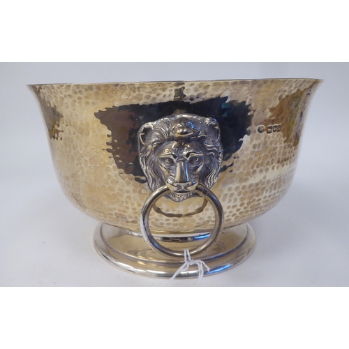 65 - A George V silver punch bowl with spot-hammered finish, a flared rim and opposing twin lion masks an... 