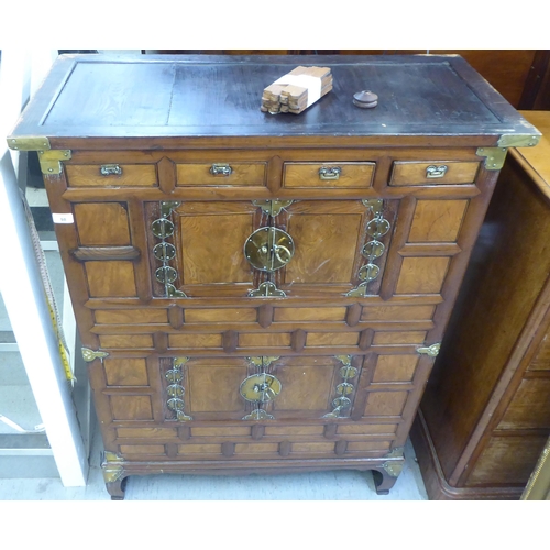 98 - A late 19th/early 20thC Chinese panelled elm and brass mounted cabinet, comprising an arrangement of... 