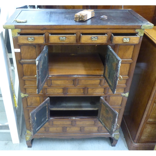 98 - A late 19th/early 20thC Chinese panelled elm and brass mounted cabinet, comprising an arrangement of... 