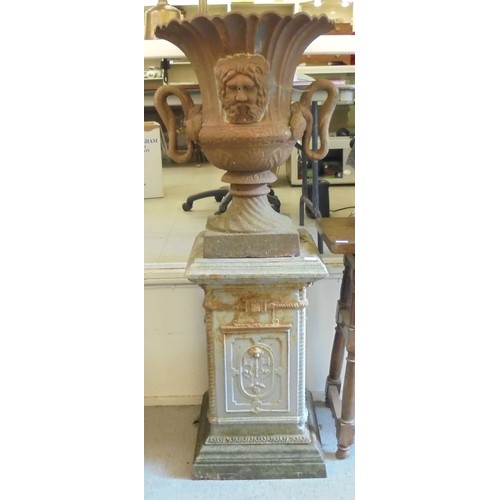 89 - A cast iron terrace urn with a flared rim, opposing ring handles and masks, on a pedestal foot  30