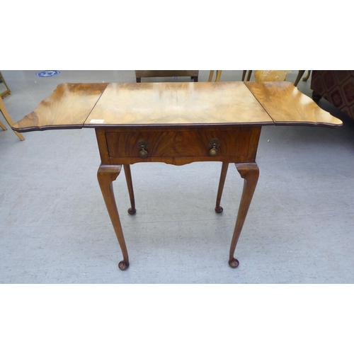 111 - A 1930s Pembroke style walnut finished, butterfly top side table with a frieze drawer, raised on sle... 