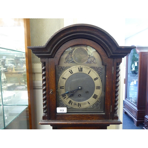 113 - An early 20thC oak cased granddaughter clock, the arched hood decorated with barleytwist columns, th... 