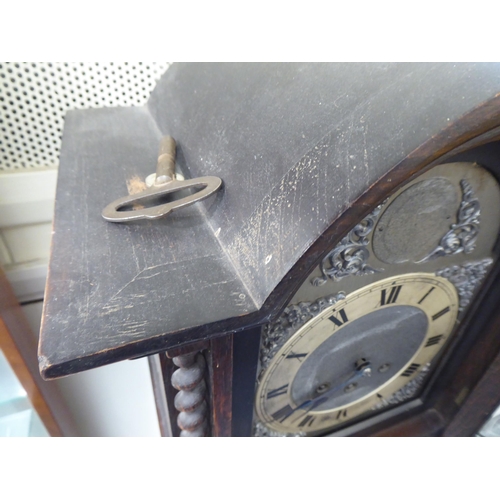 113 - An early 20thC oak cased granddaughter clock, the arched hood decorated with barleytwist columns, th... 