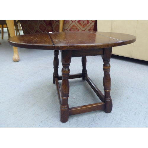 116 - A modern stained oak joint stool design coffee table with a rotating oval top and fall flaps  1... 