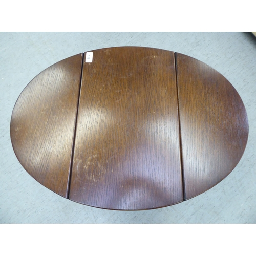 116 - A modern stained oak joint stool design coffee table with a rotating oval top and fall flaps  1... 