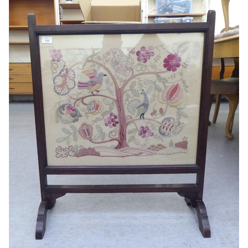 133 - A 1920s oak framed tapestry panel, freestanding firescreen, depicting stylised birds and flora ... 