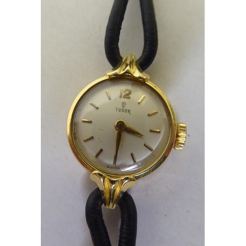 181 - A lady's Tudor 18ct gold cased wristwatch, faced by a baton dial, on a black hide strap