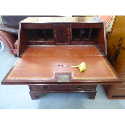 243 - A George III mahogany bureau, the fall-flap over four graduated drawers, raised on bracket feet ... 