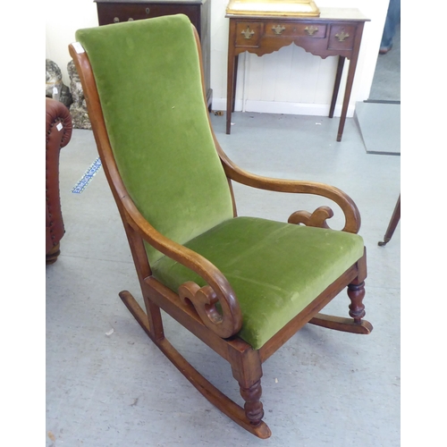 251 - A late Victorian mahogany showwood framed, open arm rocking chair, upholstered in green fabric