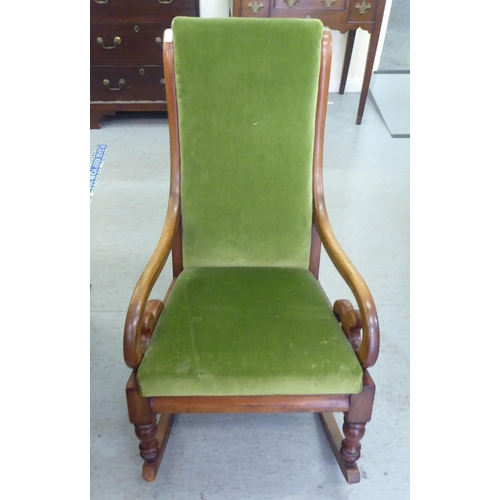 251 - A late Victorian mahogany showwood framed, open arm rocking chair, upholstered in green fabric